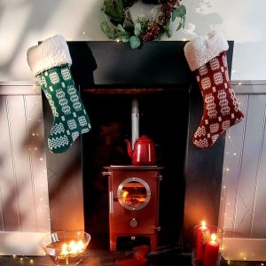 Chilli Penguin fire stove, charred red in a brick alcove on a slate hearth with Christmas stockings on the mantel